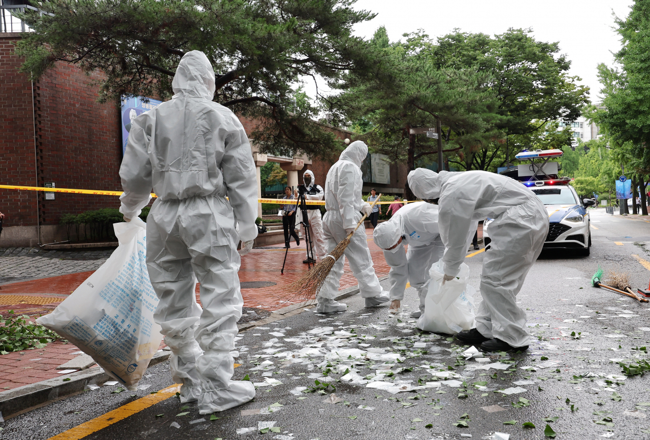 This photo shows workers on Wednesday morning handling waste contained in a balloon flying from North Korea near the Jeondong Theater in Jung-gu, central Seoul,. (Yonhap)