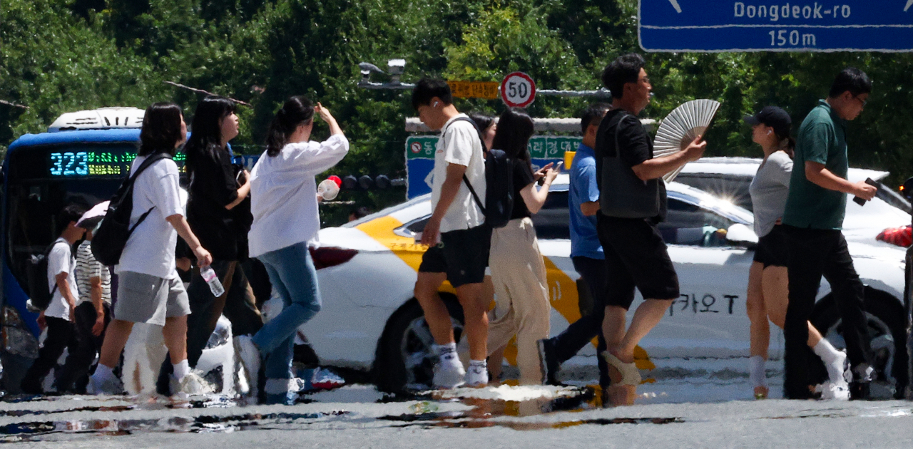 Pedestrians walk amid the heat haze forming above the streets in Daegu, Monday, where daytime temperatures reached as high as 36 degrees Celsius. (Yonhap)